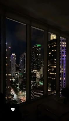 the city is lit up at night with lights on and buildings in the distance from an apartment window