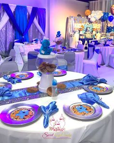 a table set up for a baby's first birthday party with blue and purple decorations