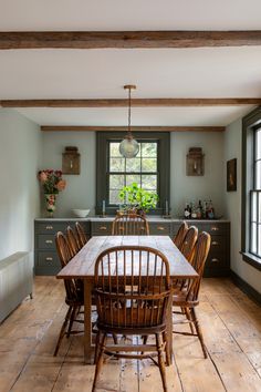 a dining room table and chairs in front of an open kitchen area with wood flooring