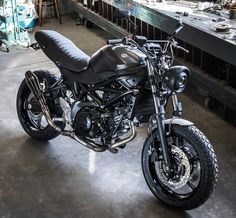 a black motorcycle parked in a garage next to a table with other tools on it