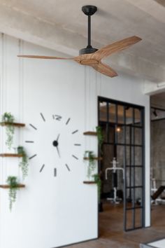 a clock mounted to the side of a wall in front of a doorway with plants growing on it