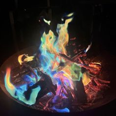 the fire is glowing brightly in the dark with blue and yellow flames coming out of it