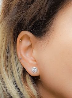 a close up of a person wearing a pair of ear piercings with diamonds on them