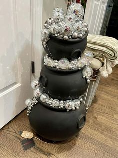 a stack of black vases sitting on top of a wooden floor next to a white door