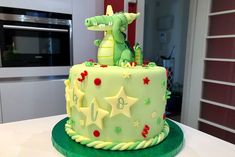 a birthday cake decorated with green icing and stars on the top, sitting on a table