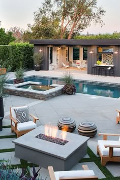 an outdoor fire pit in the middle of a backyard with chairs and tables around it