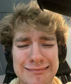 a man with his eyes closed and nose piercing in front of him is smiling at the camera