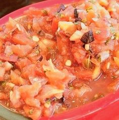 a red bowl filled with lots of food on top of a table