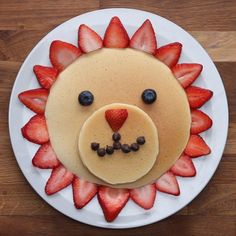 a plate with pancakes and strawberries in the shape of a lion's face