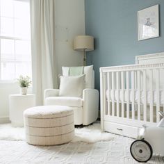 a baby's room with blue walls and white furniture