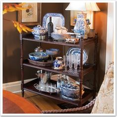 a wooden shelf filled with blue and white dishes on top of a hard wood floor