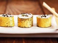 three small cakes on a white plate with chopsticks