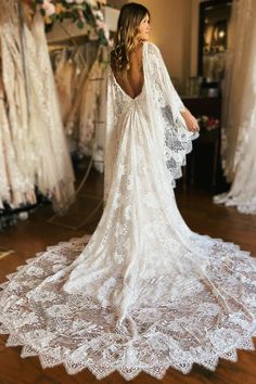 the back of a woman's wedding dress in front of dresses on mannequins