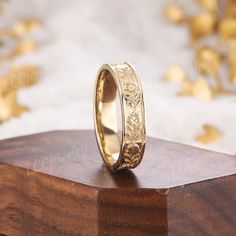 a gold wedding ring sitting on top of a wooden block