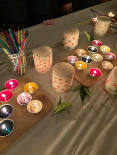 many candles are lit on a table with flowers and other items around it in front of them