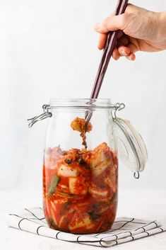 someone is holding chopsticks in a jar full of food