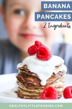 a young boy is smiling while looking at pancakes with raspberries on top and the text overlay reads, banana pancakes 2 ingredients