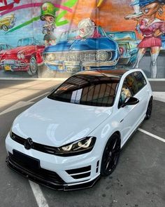 a white car parked in front of a colorful wall