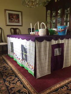 a table covered with a purple and white tent on top of a red area rug