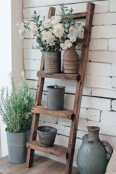 an old wooden ladder is used as a shelf for flower pots and other vases