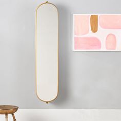 a mirror hanging on the wall next to a stool with a footstool in front of it