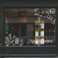 the window of a store with drawings on it's glass and writing in front