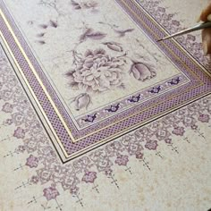 a person is cutting paper with scissors on a tablecloth that has flowers and butterflies on it