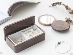 an open jewelry box sitting on top of a table next to a mirror and bracelet