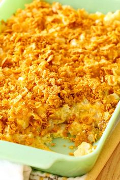 a green casserole dish filled with food on top of a wooden table