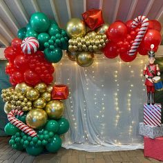 balloon arch with nutcracker and candy canes in front of curtained backdrop