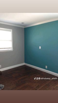 an empty room with blue walls and wood floors