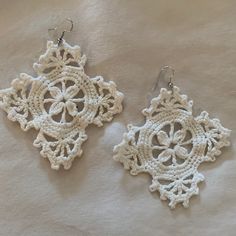 two crocheted white earrings on top of a piece of paper