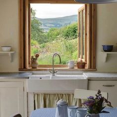 a kitchen with a sink, window and blue table cloth on the dining room table