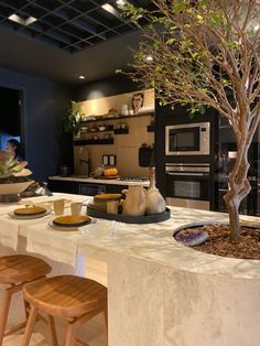 a tree in the middle of a kitchen with plates and bowls on the counter top