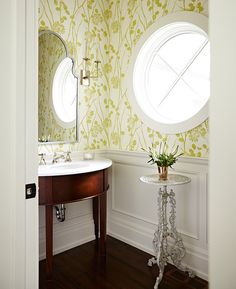 a white sink sitting under a round window in a bathroom