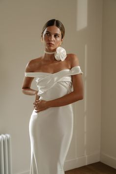 a woman in a white dress standing next to a radiator with her hands on her hips