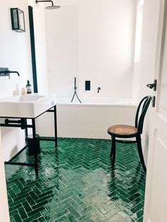 a bathroom with green flooring and a chair in the corner next to the bathtub