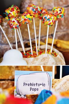 there are many colorful lollipops on sticks in the bowl and next to it is a sign that says prehistoriic pops