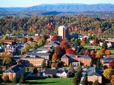 an aerial view of a campus surrounded by trees and mountains in the background with autumn foliage