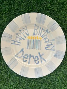 a birthday plate with candles on it sitting in the grass