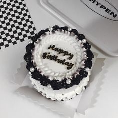 a white and black birthday cake with the words happy birthday written in it's center