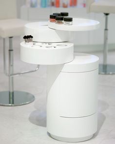 a white table with two hairbrushes on it and some stools in the background