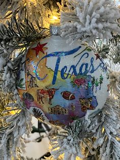 a christmas ornament hanging from a tree with the word texas painted on it