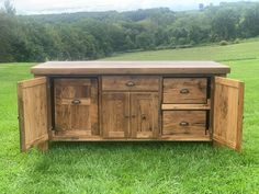 a large wooden cabinet sitting on top of a lush green field