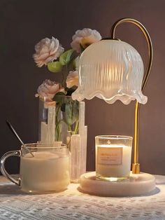 a table topped with candles and flowers next to a vase filled with water on top of a table