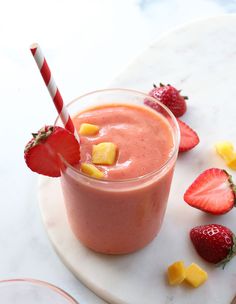 a smoothie with strawberries and pineapple on the side