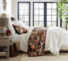 a bed with white sheets and pillows in a room next to a large black window