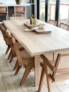 a wooden table with chairs around it in front of large windows and an open floor plan