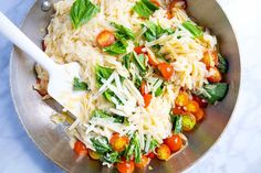 a pan filled with pasta and vegetables on top of a table