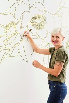 a woman is drawing flowers on the wall